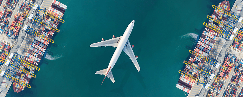 Aerial view of a passenger aircraft flying over a container port